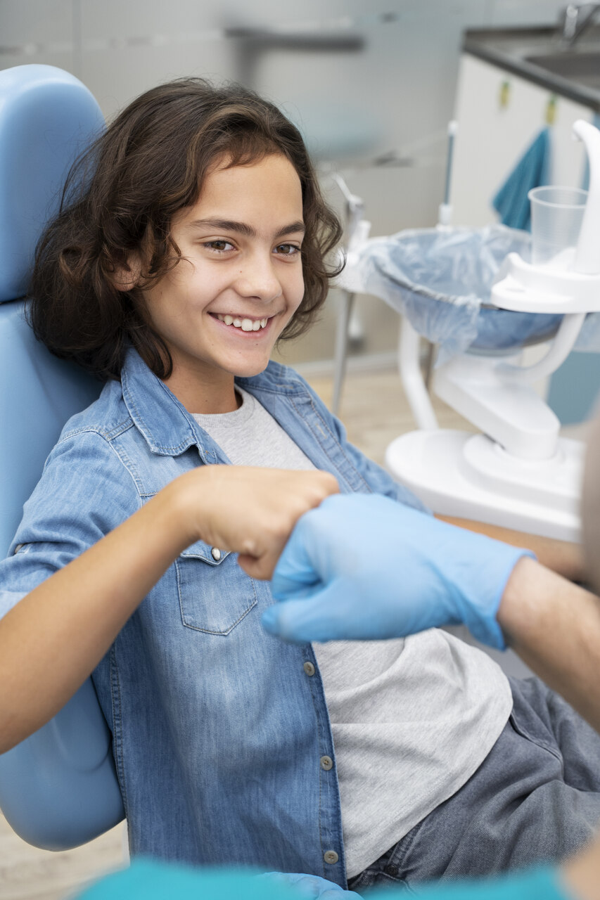 Criança no dentista cumprimentando o profissional odontológico pára conscientizar sobre os principais problemas odontológicos na infância.