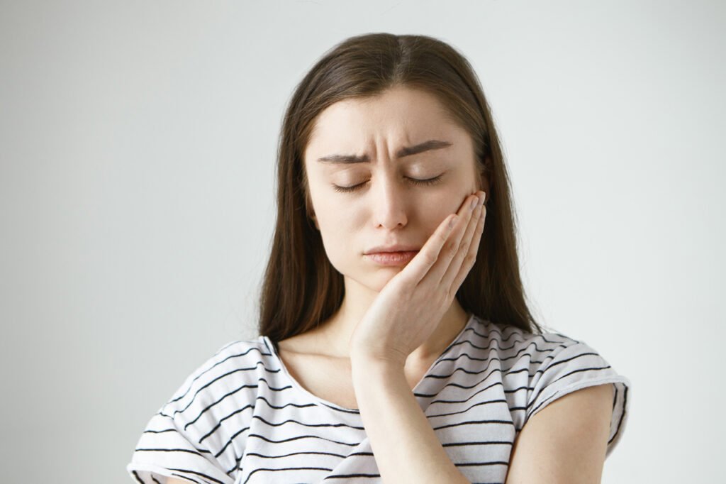 Mulher com dor de dente por conta da periodontite.