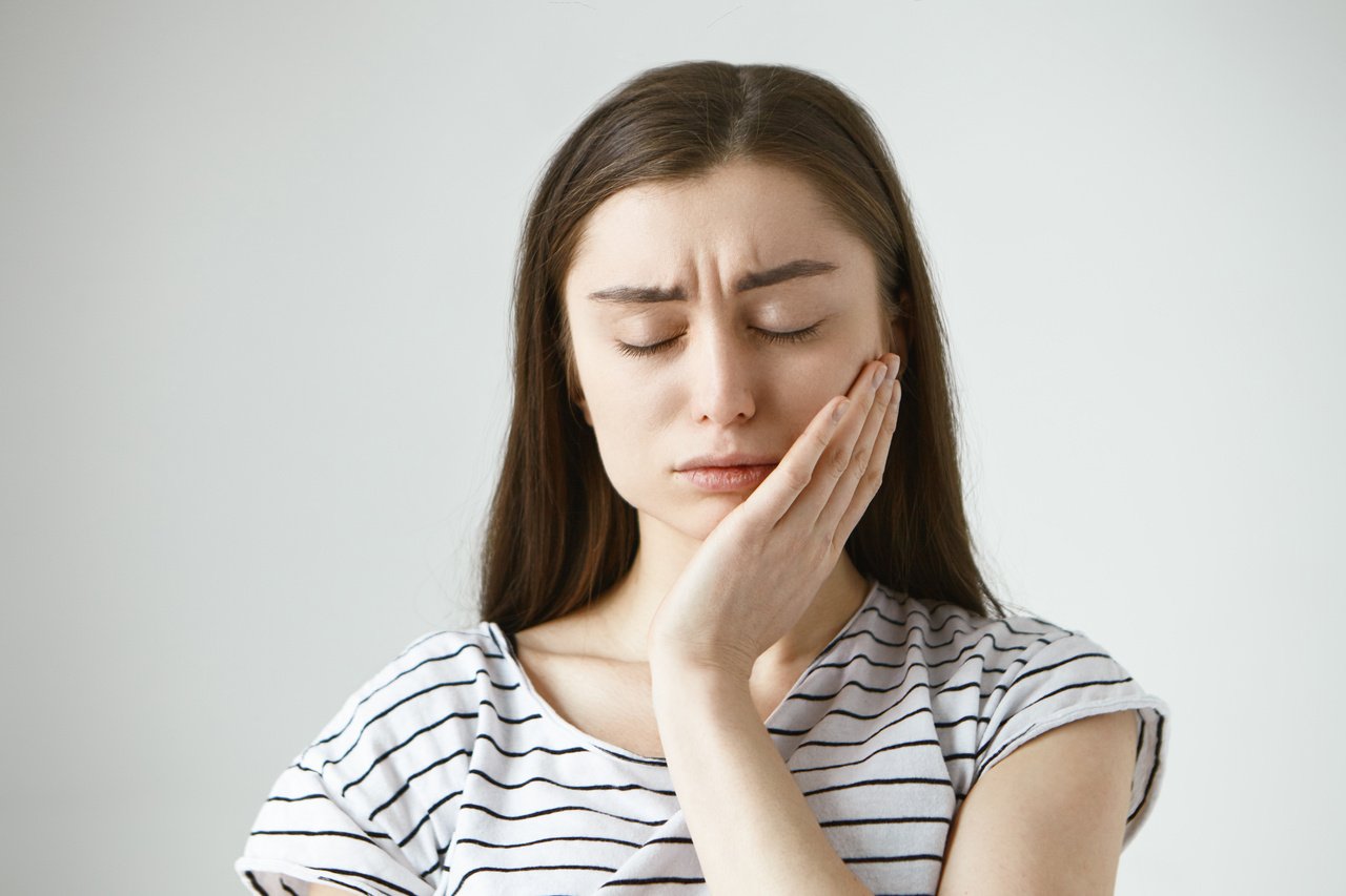 Mulher com dor de dente por conta da periodontite.